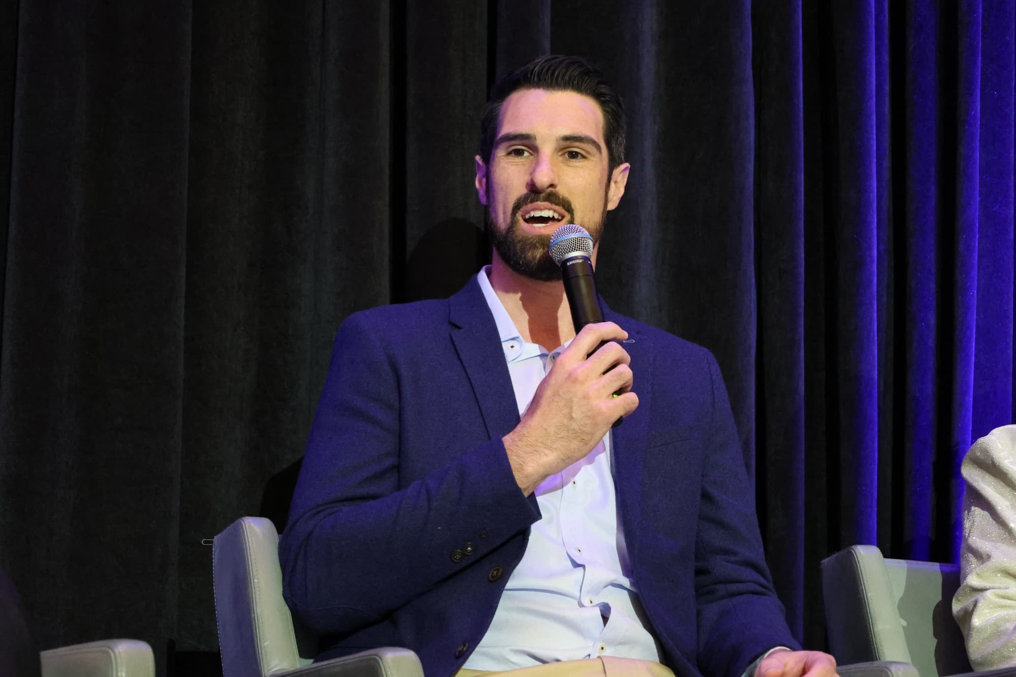 Josh Horneman speaking on a panel, microphone in hand